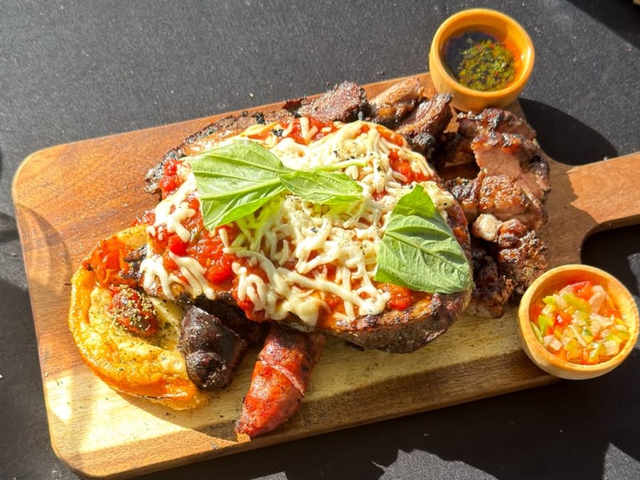 Traditional Argentine mixed grill board with vacío, chorizo, morcilla, sweetbreads and provoleta, served alongside pizza-style pork matambrito, chimichurri and salsa criolla