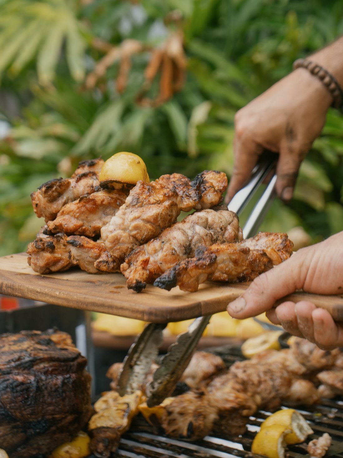 Grilled chicken lifted straight off the fire, more cuts still cooking below