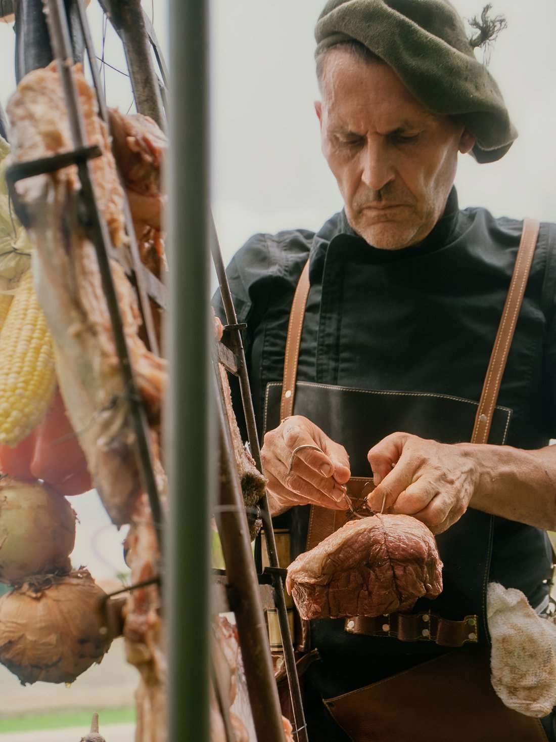 Chef tying a whole cut onto the asador cross before it goes over the fire
