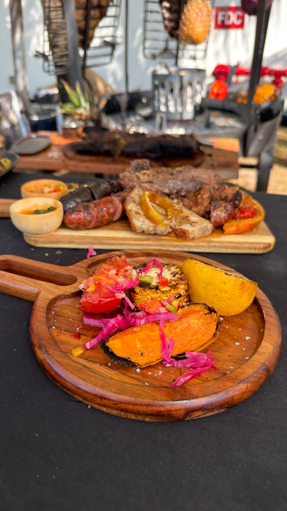 Overhead shot of a grilled asado board with flank steak, chorizo, morcilla, provoleta and fire-roasted pineapple