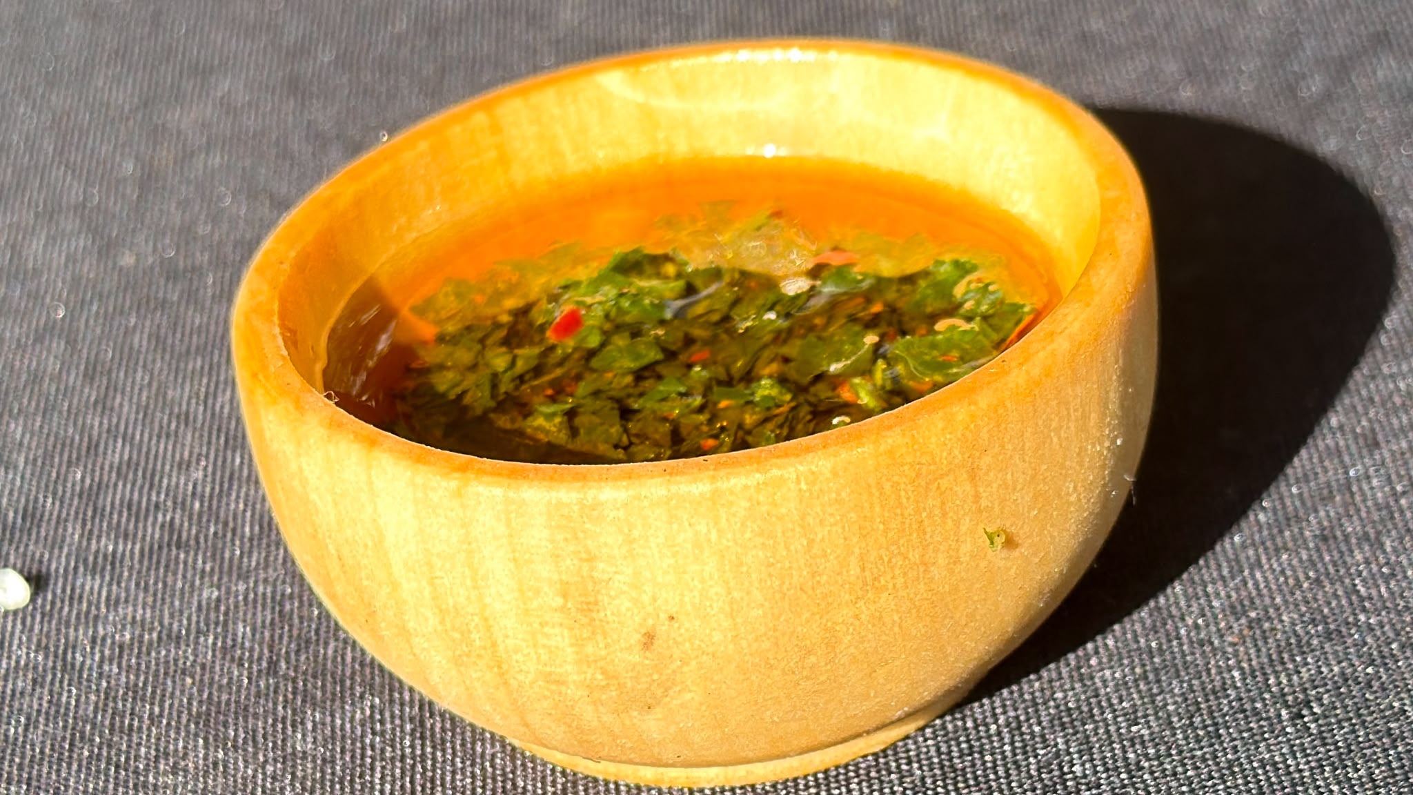 Traditional Argentine chimichurri with parsley, garlic and crushed red pepper in a small wooden bowl