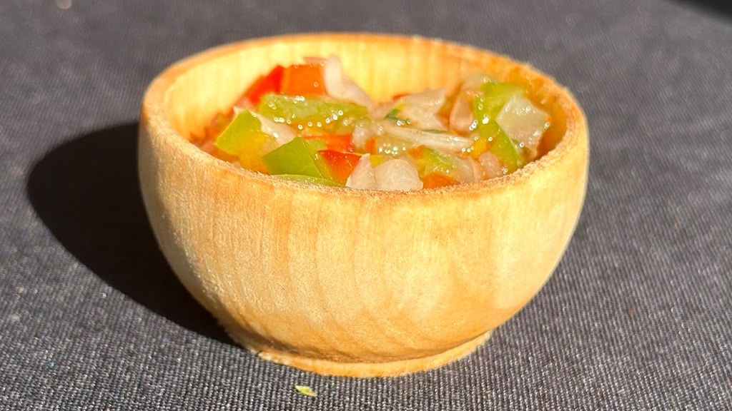 Argentine salsa criolla with bell peppers, onion and ember-roasted mandarin in a small wooden bowl